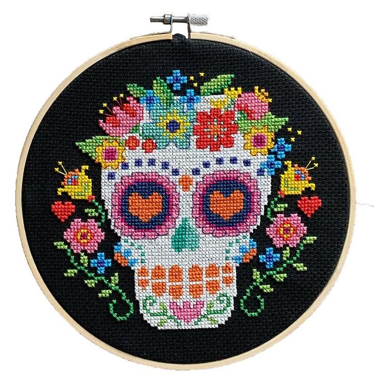 a cross stitched skull with flowers on it's head is shown in the hoop