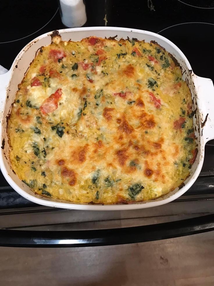 a casserole dish sitting on top of an oven with broccoli and cheese