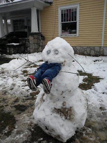 a child is sitting on top of a snowman