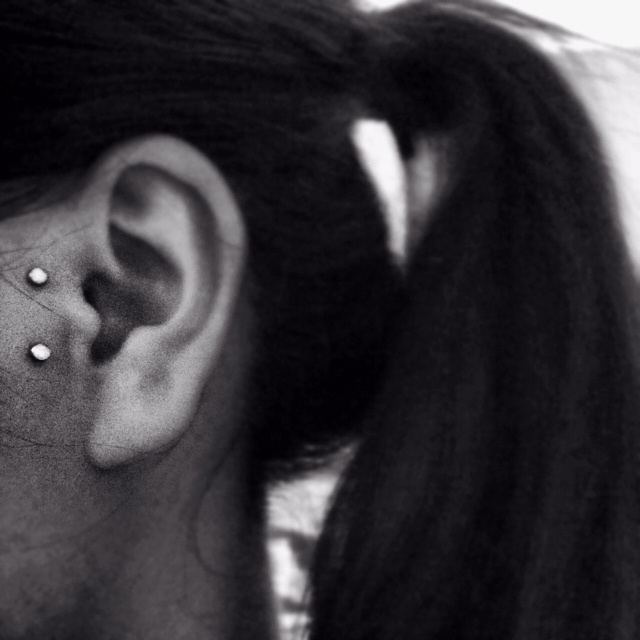 a close up of a person with ear piercings on their ears and behind them is a black and white photo