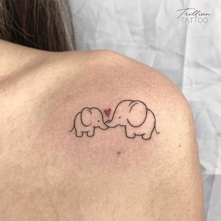 an elephant tattoo on the back of a woman's shoulder, with two elephants touching each other