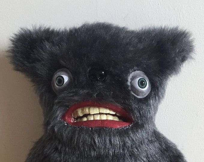 a black stuffed animal with big eyes and teeth