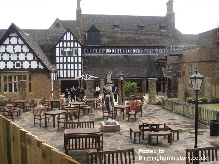 an outdoor area with tables and benches in front of a large building that has many windows