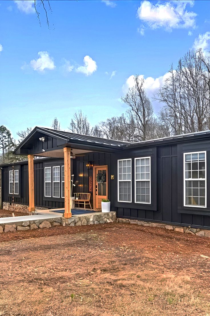 a black house sitting on top of a dirt field