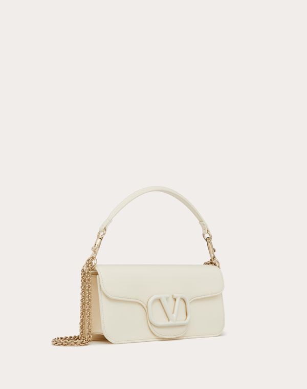 Valentino Garavani Locò shoulder bag in calfskin leather with enamel tone-on-tone VLogo Signature detail. Equipped with both a detachable sliding chain strap and a detachable handle, this accessory can be worn as a crossbody/shoulder bag or carried as a handbag. - Platinum-finish hardware - Magnetic closure with logo - Removable leather handle - Shoulder strap with removable sliding chain - Nappa leather lining. Interior: one slip pocket Shoulder strap drop length: min. 26 cm / 10.2 in. to max. High-end Cream Shoulder Bag For Evening, Designer Baguette Shoulder Bag With Adjustable Strap, Designer White Calf Leather Shoulder Bag, Luxury Baguette Shoulder Bag With Detachable Handle, Luxury Baguette Shoulder Bag With Detachable Strap, White Calf Leather Satchel Shoulder Bag, Luxury Shoulder Baguette Bag With Gold-tone Hardware, Cream Calf Leather Bags With Palladium Hardware, White Rectangular Calf Leather Shoulder Bag