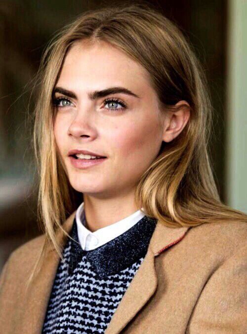 a woman with long hair and blue eyes wearing a brown jacket, white shirt and black tie