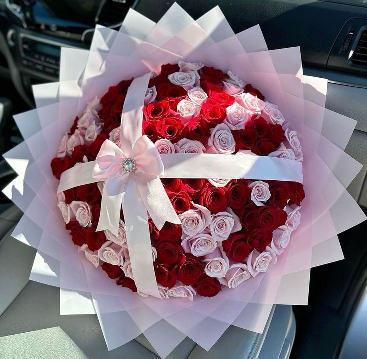 a bouquet of roses in the shape of a heart sitting on top of a car dashboard