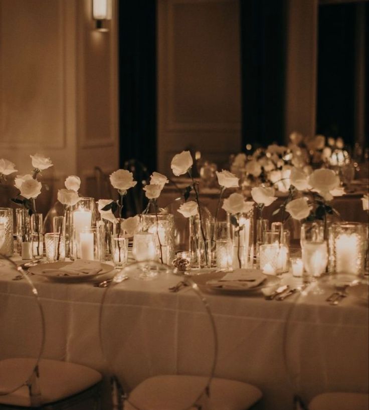 a long table with candles and flowers in glass vases on top of each other