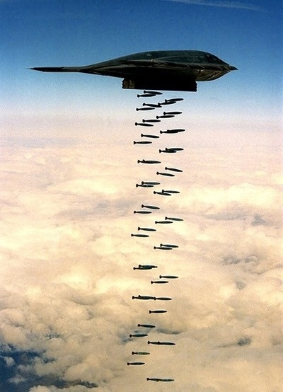 an airplane flying in the sky with many missiles attached to it