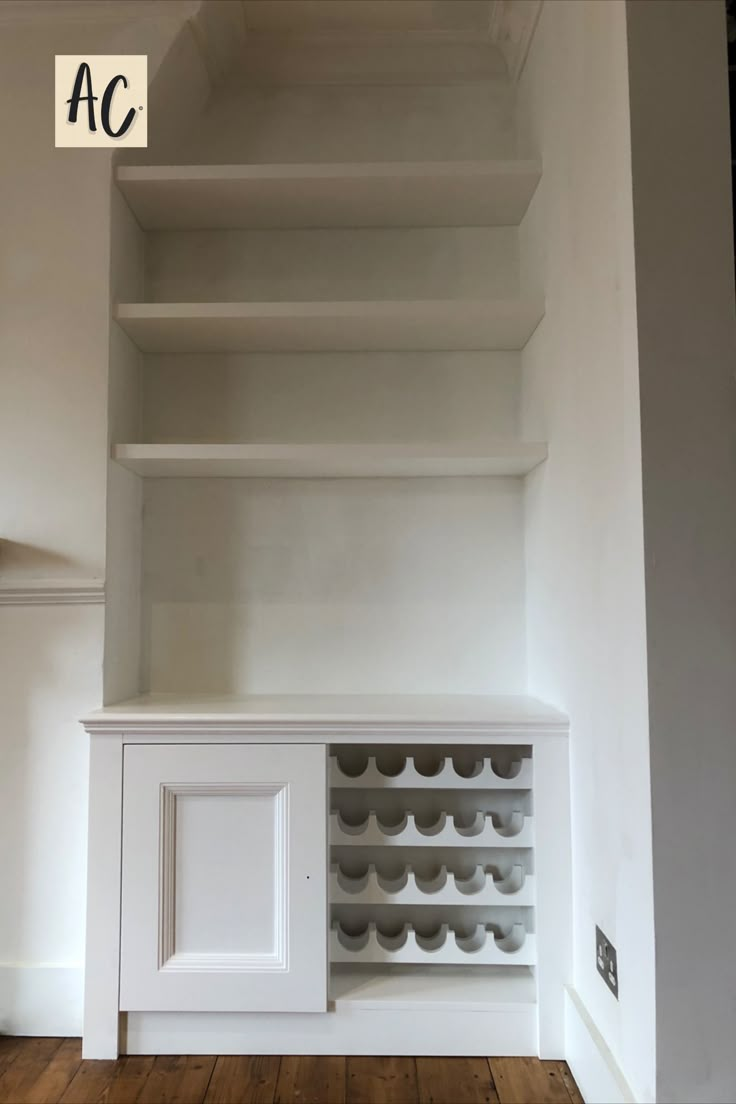 an empty white shelf with wine glasses on it in a room that has wood floors