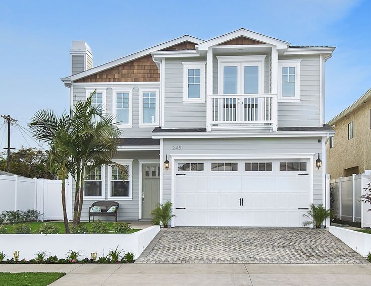 a white house with two garages and palm trees