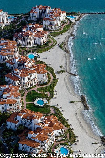 an aerial view of the beach and ocean in front of some buildings with orange roofs