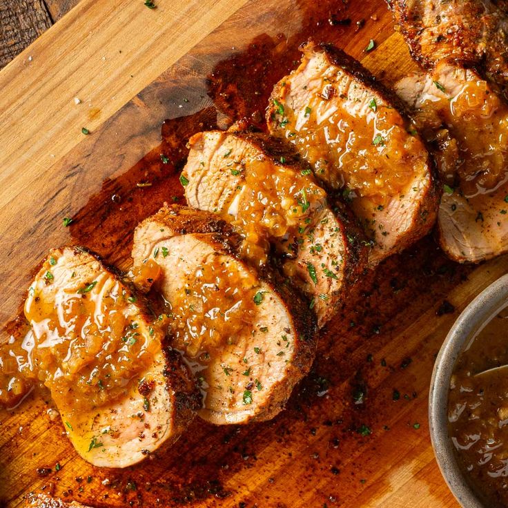 sliced pork chops on a cutting board next to a bowl of gravy