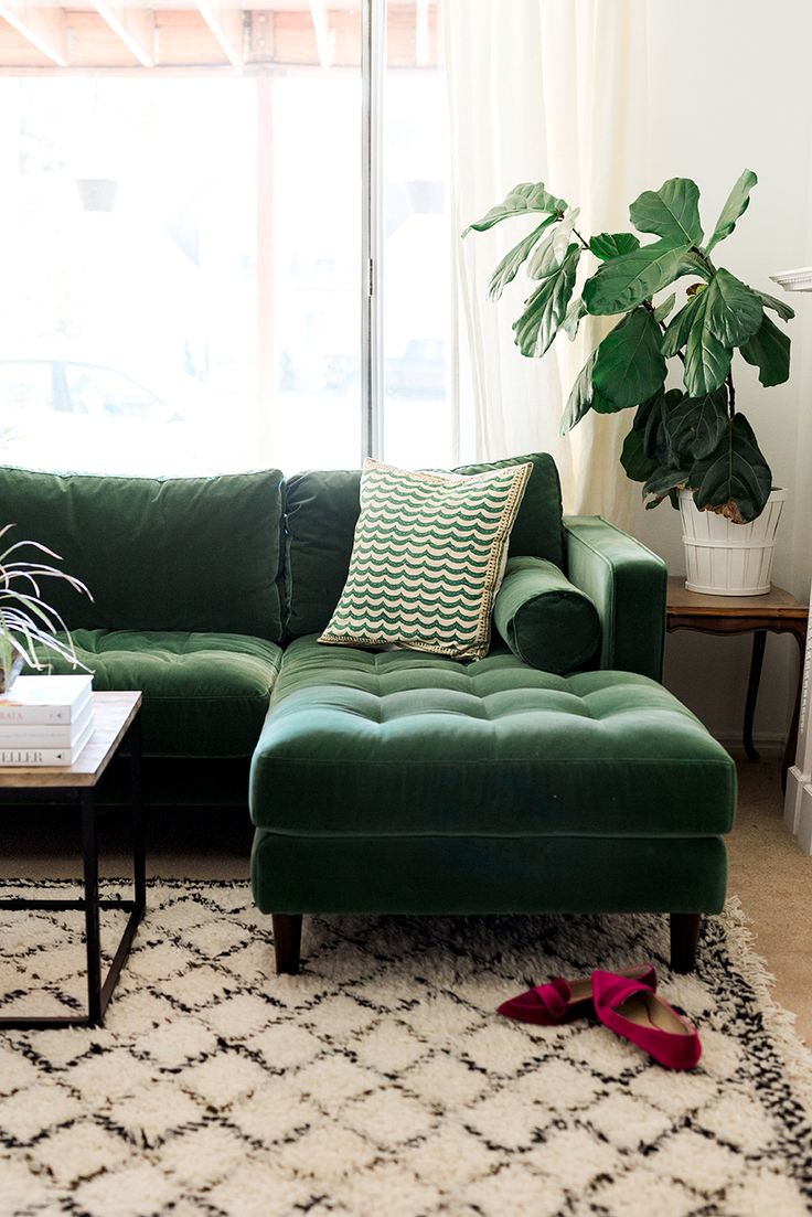 a living room with a green couch and white rug