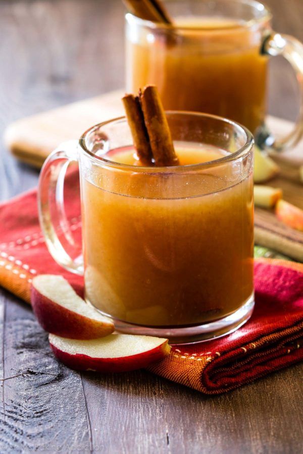 two mugs filled with apple cider and cinnamon sticks