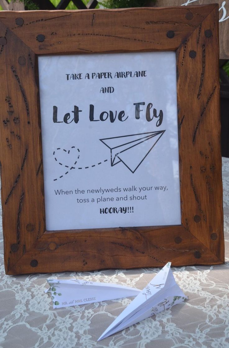 a wooden frame sitting on top of a table next to a paper airplane and a sign that says let love fly