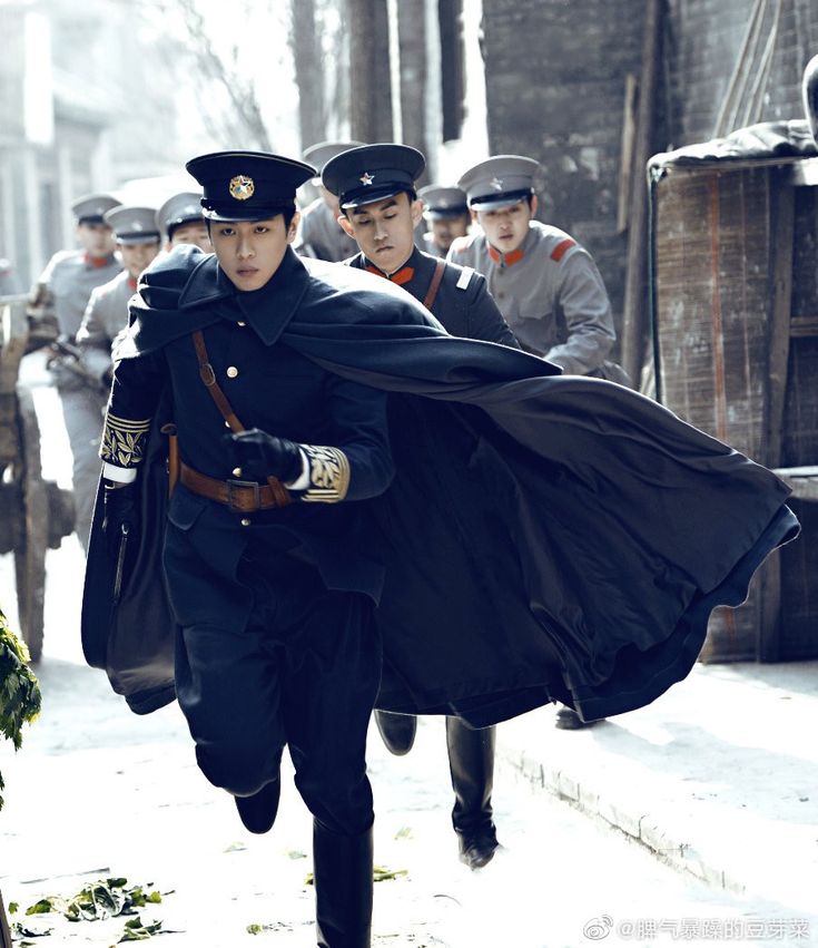 a man dressed as a police officer running down the street with other men behind him