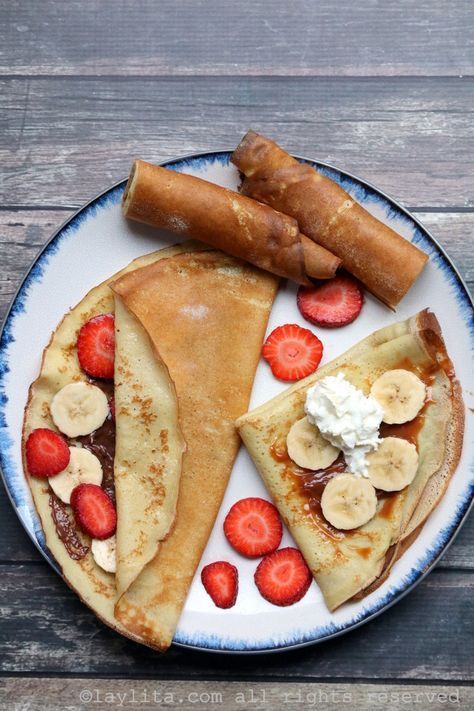 a plate topped with pancakes and fruit on top of a wooden table