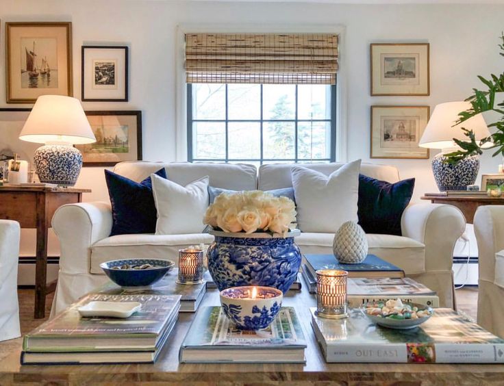 a living room filled with white furniture and lots of books on top of a coffee table