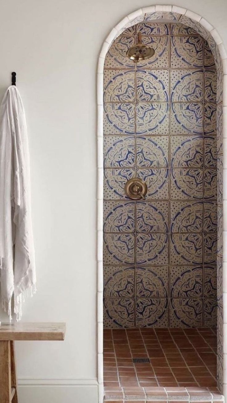 a bathroom with an arched door and tile flooring, along with a wooden bench