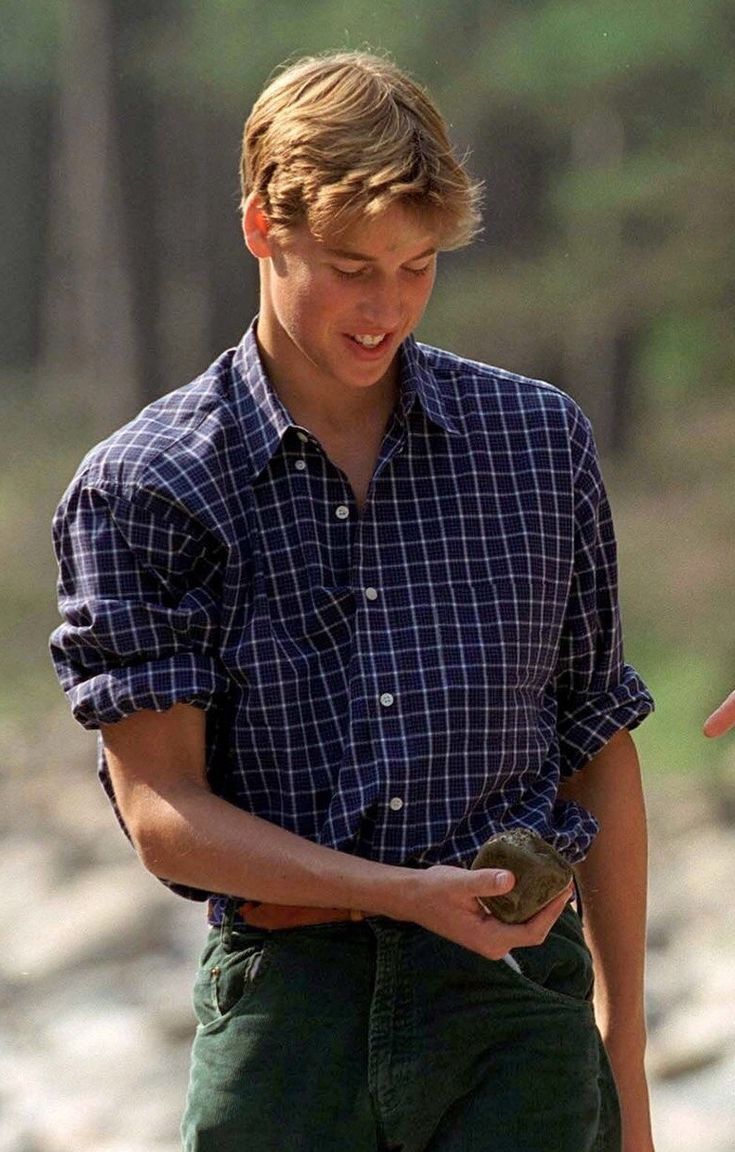 a young man is holding a bird in his right hand and looking down at it