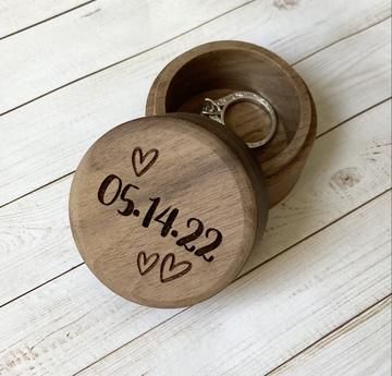 two wedding rings in a wooden box with the date on it's front and back