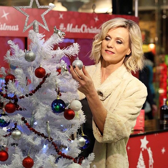 a woman is decorating a white christmas tree