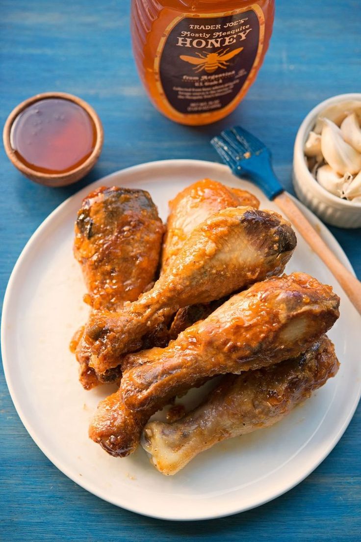 two pieces of chicken on a white plate with honey