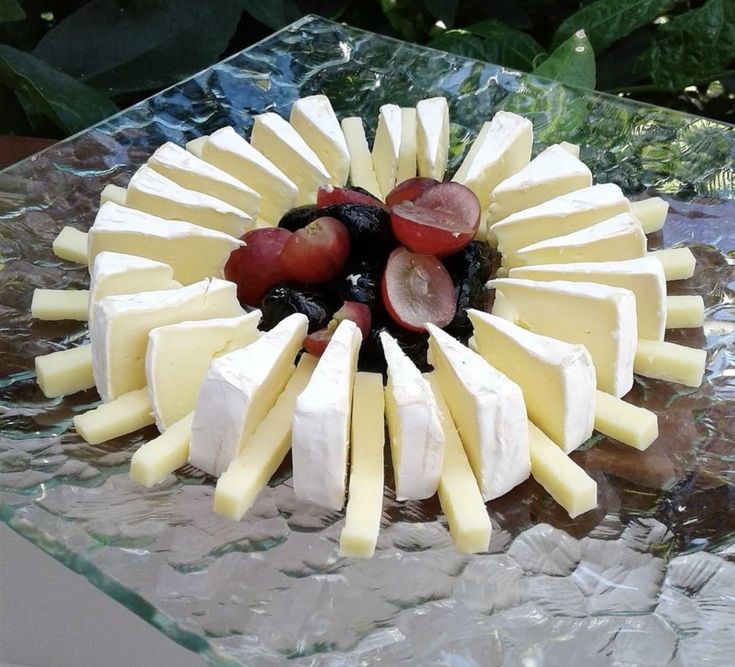 cheese and fruit arranged in a circular arrangement on a glass platter