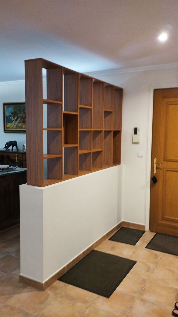 a living room filled with furniture next to a wooden door and brown book shelf on the wall