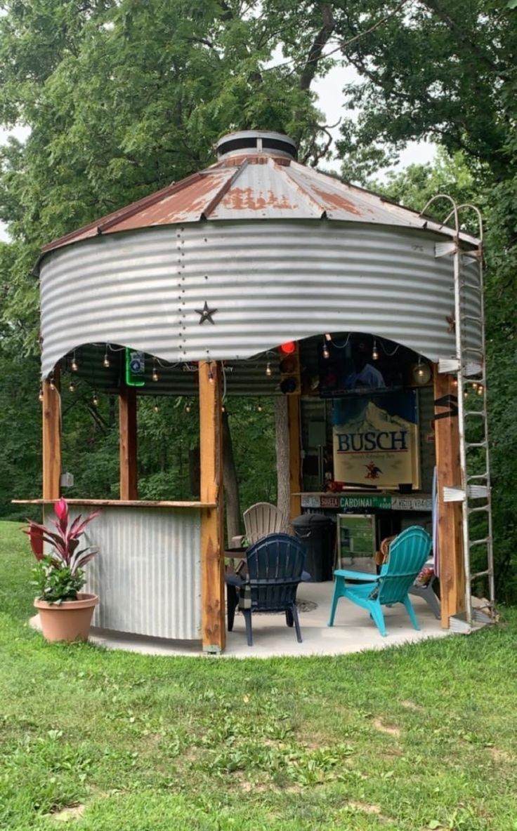 an outdoor bar in the middle of a field with blue chairs and lights on it