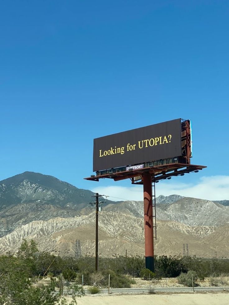 a billboard with the words looking for utopia on it in front of mountains and trees