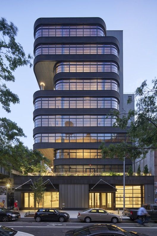 an office building with many windows and cars parked in front of it at night time