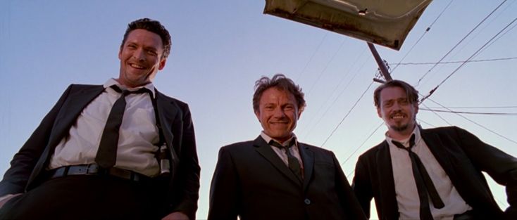 three men standing next to each other in front of a street sign and telephone pole