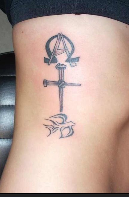 a woman's lower back tattoo with an anchor and cross on the bottom side