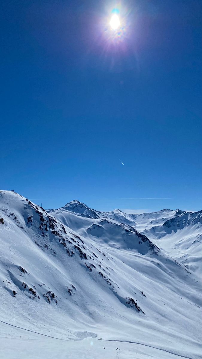 the sun shines brightly over a snowy mountain