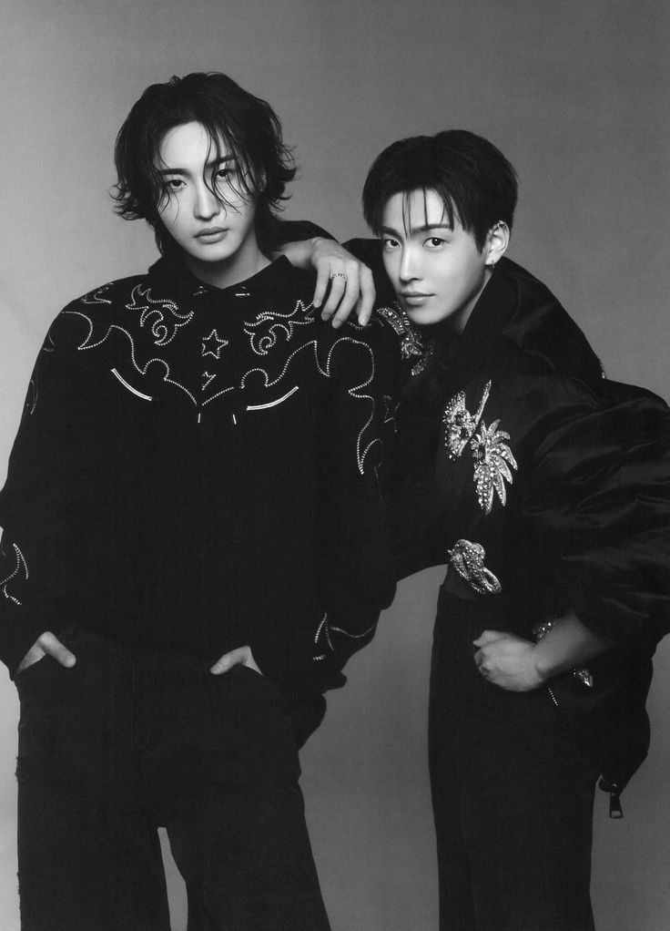 two young men standing next to each other in black and white outfits, one with his arm around the other's shoulder