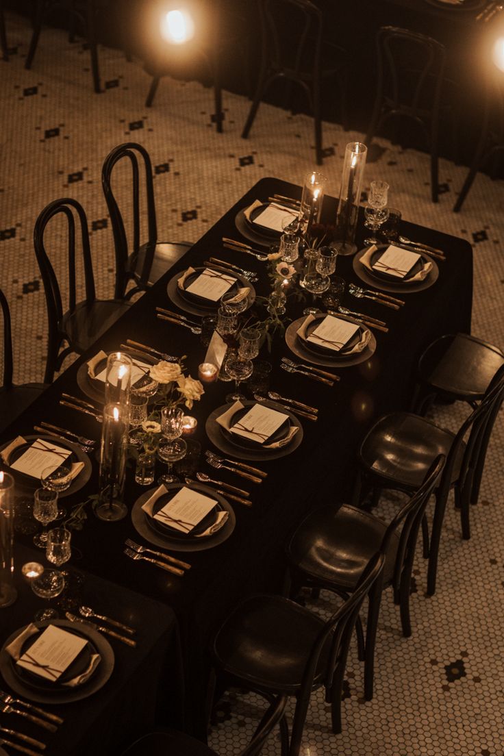 a long table set up with place settings and candles on it for an elegant dinner