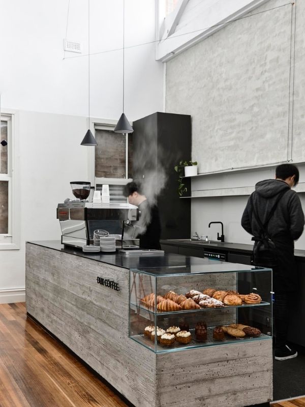 a man standing in front of a counter filled with donuts and other pastries