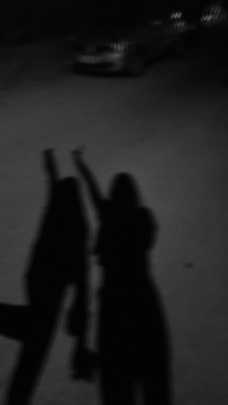 black and white photo of two people walking down the street with their arms in the air