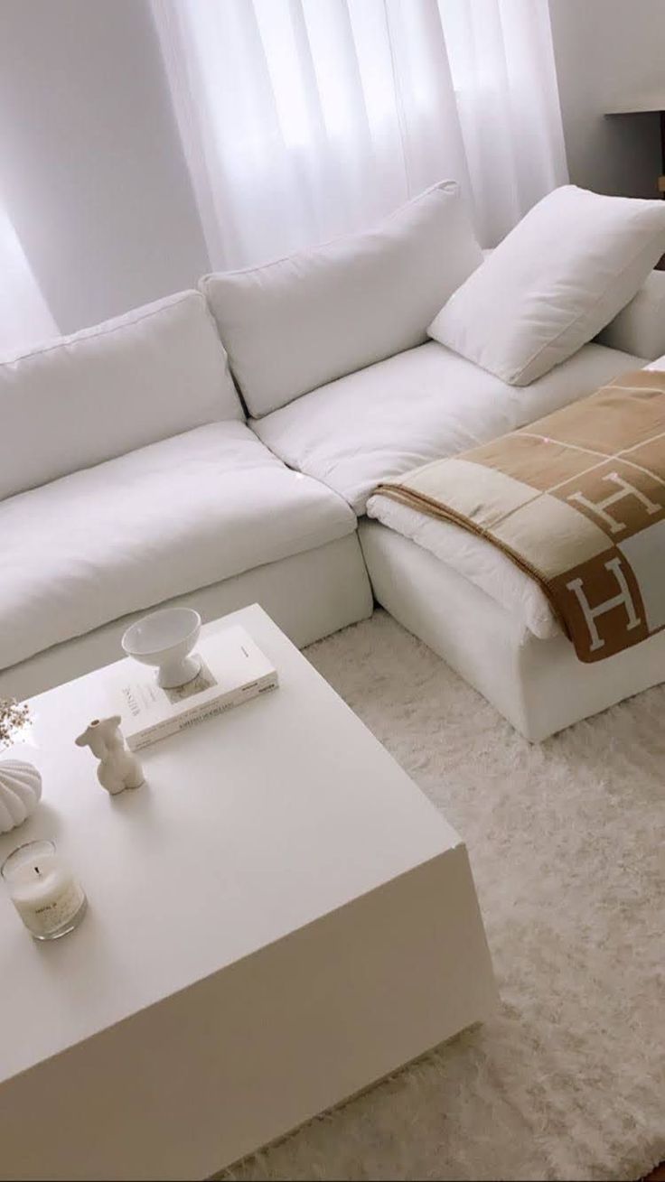 a white couch sitting next to a coffee table in a living room under a window