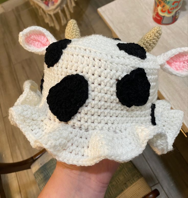 a crocheted cow hat with ears on it's head is being held up