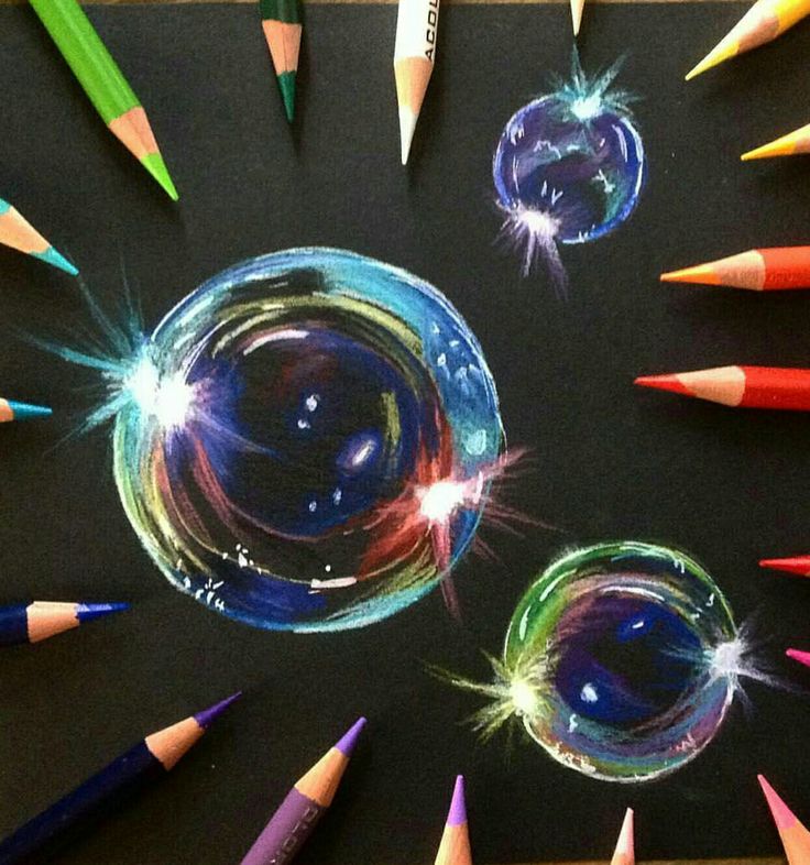 some colored pencils are laying on top of a black surface with different shapes and sizes