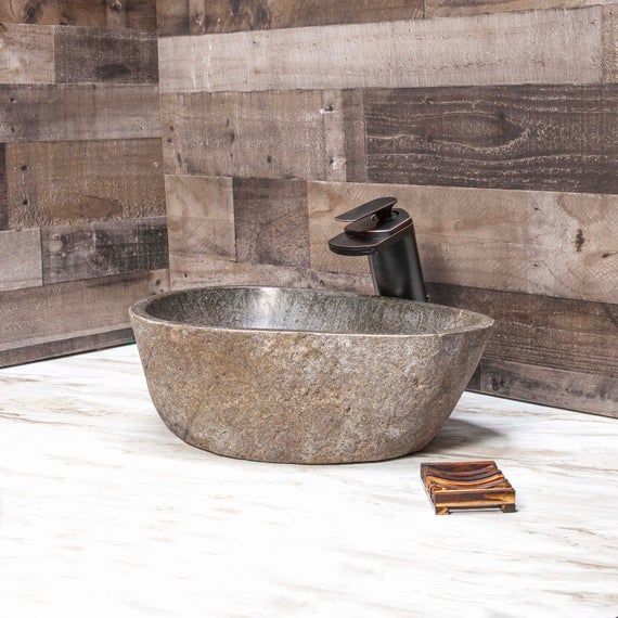 a bathroom sink sitting on top of a counter next to a wooden wall mounted faucet