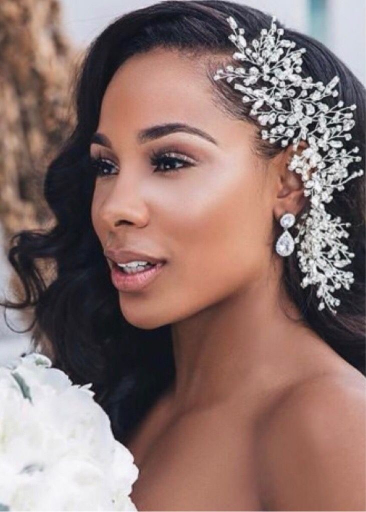 a woman wearing a bridal hair comb with flowers in her hair and holding a bouquet