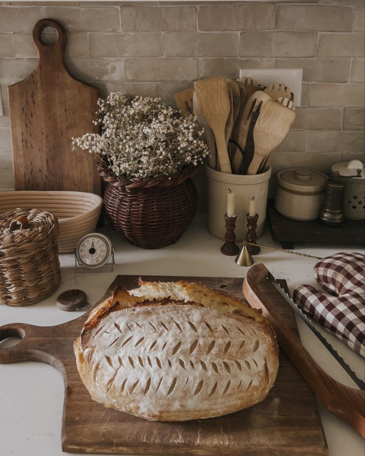 a loaf of bread sitting on top of a wooden cutting board next to other kitchen utensils