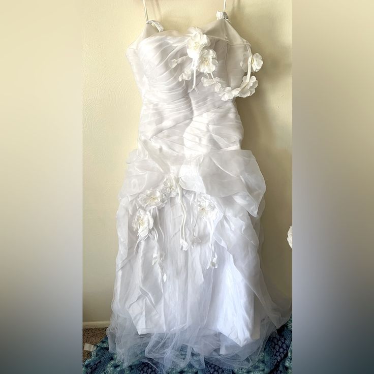 a white wedding dress hanging on a wall next to a blue and white flowered rug