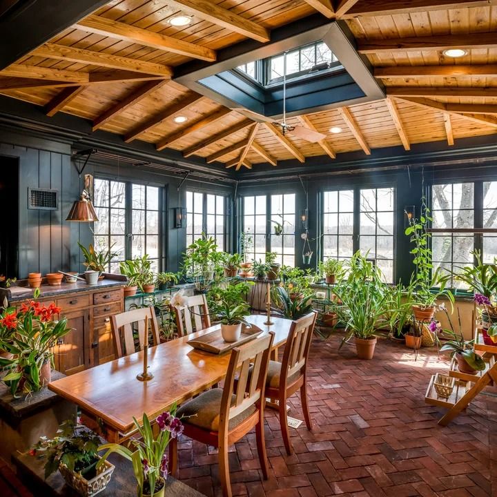 a dining room filled with wooden furniture and lots of plants on the windows sill