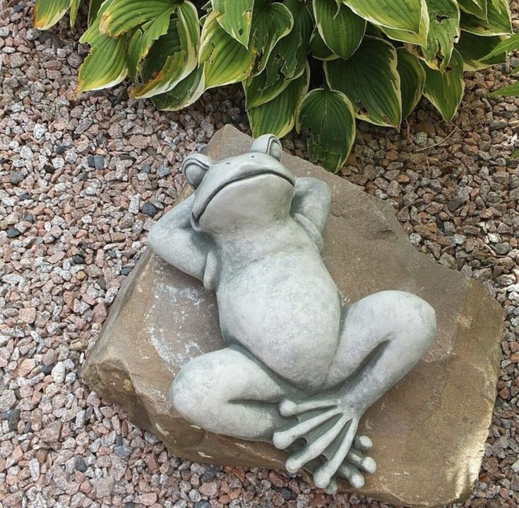 a frog statue sitting on top of a rock