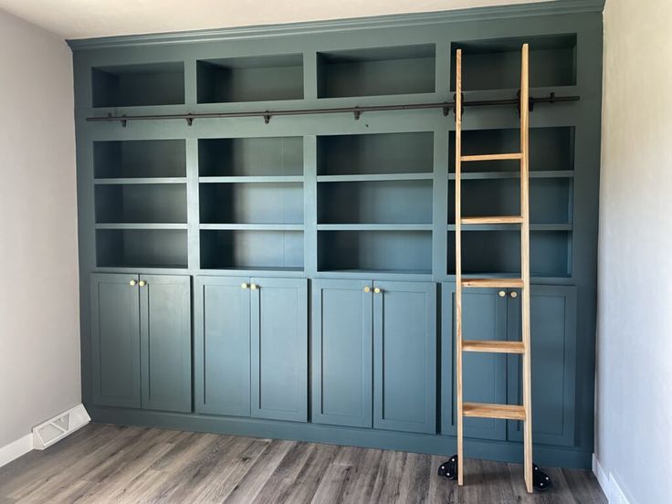 an empty room with blue bookcases and a ladder